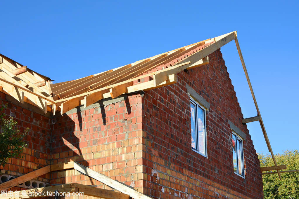 在建的房屋。木制的屋面工程施工。未完成的房屋建筑。安装的木梁施工在房子的屋顶桁架系统